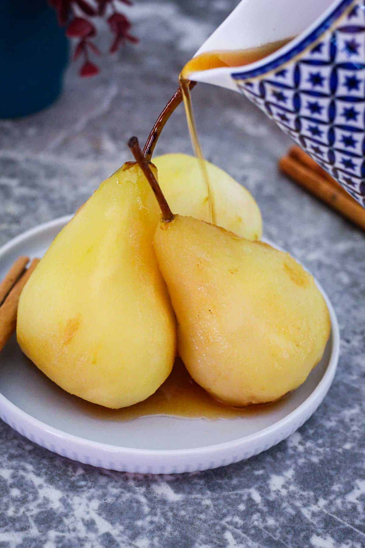 Pouring thickened syrup over the poached pears.