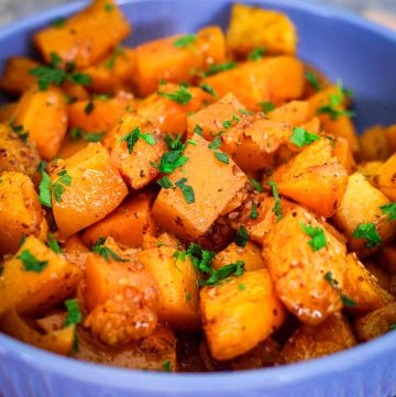 A bowl showing cubed butternut squash, roasted with herbs.