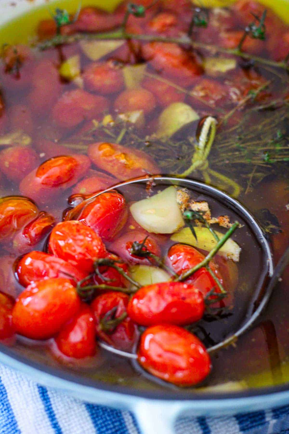 Tomatoes confit with garlic and herbs in olive oil, just roasted shown in the baking dish.