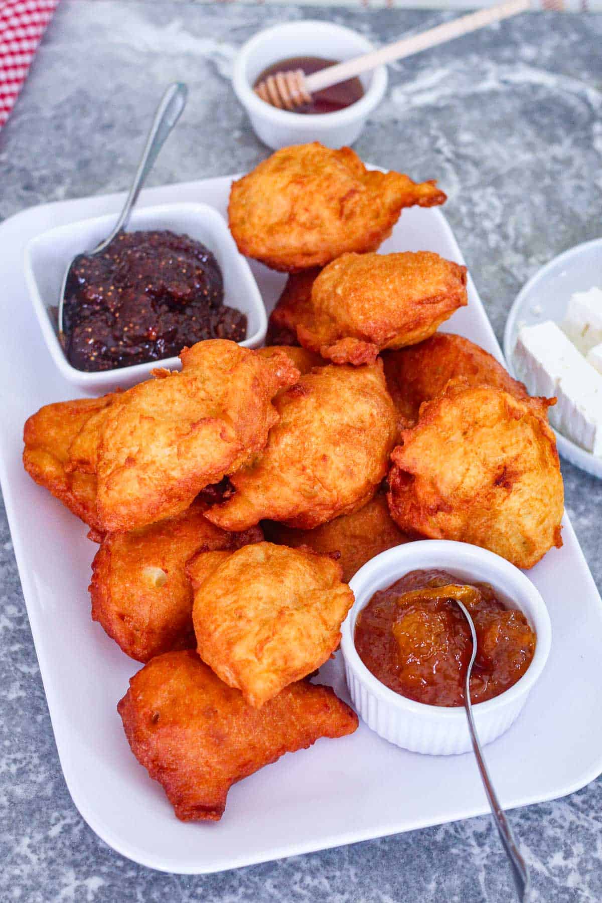 Albanian fried dough (petulla), shown on a platter served with two different jams, honey and feta cheese.