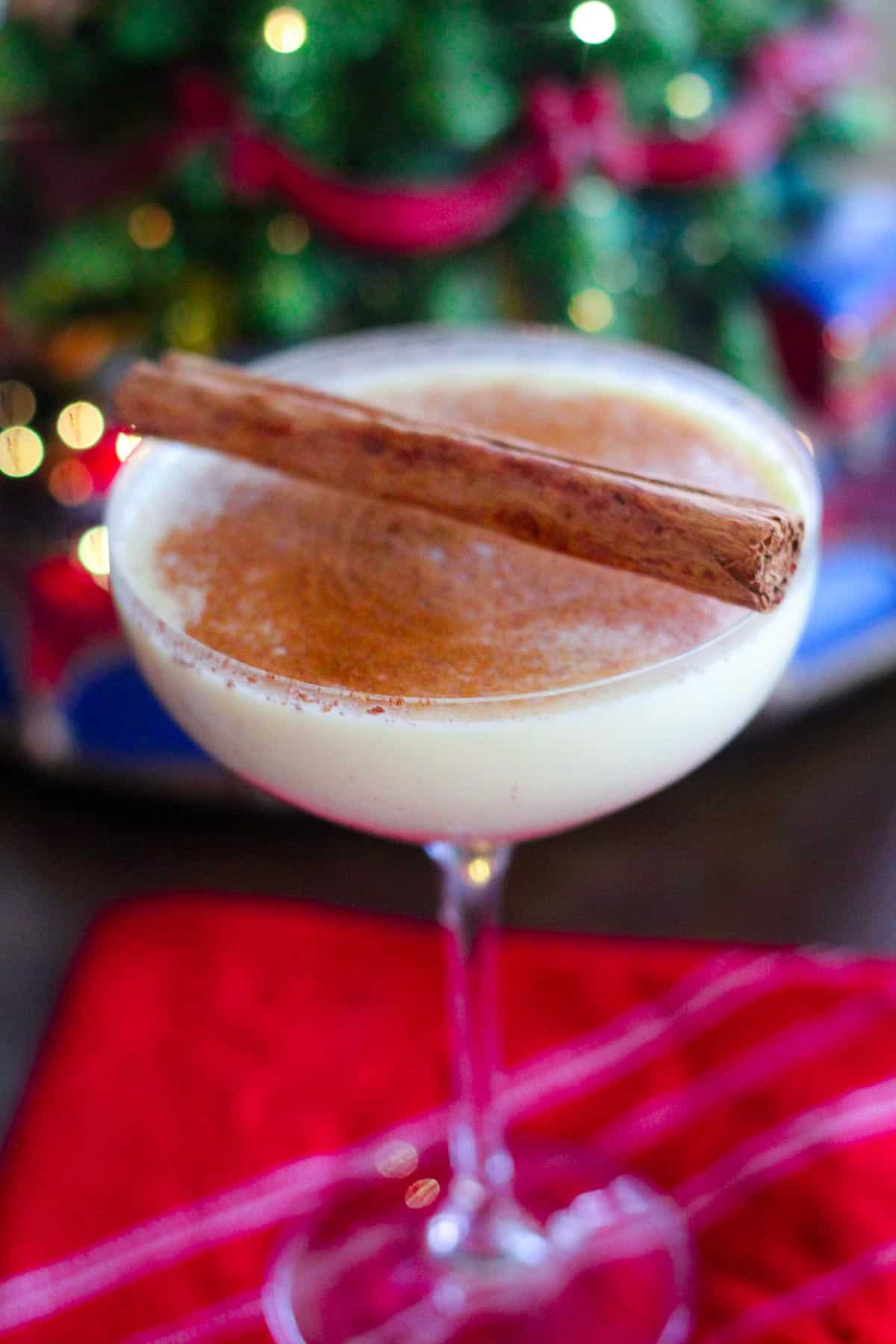 Festive eggnog cocktail with rum and kahlua over a red kitchen napkin, in front of Christmas lights.