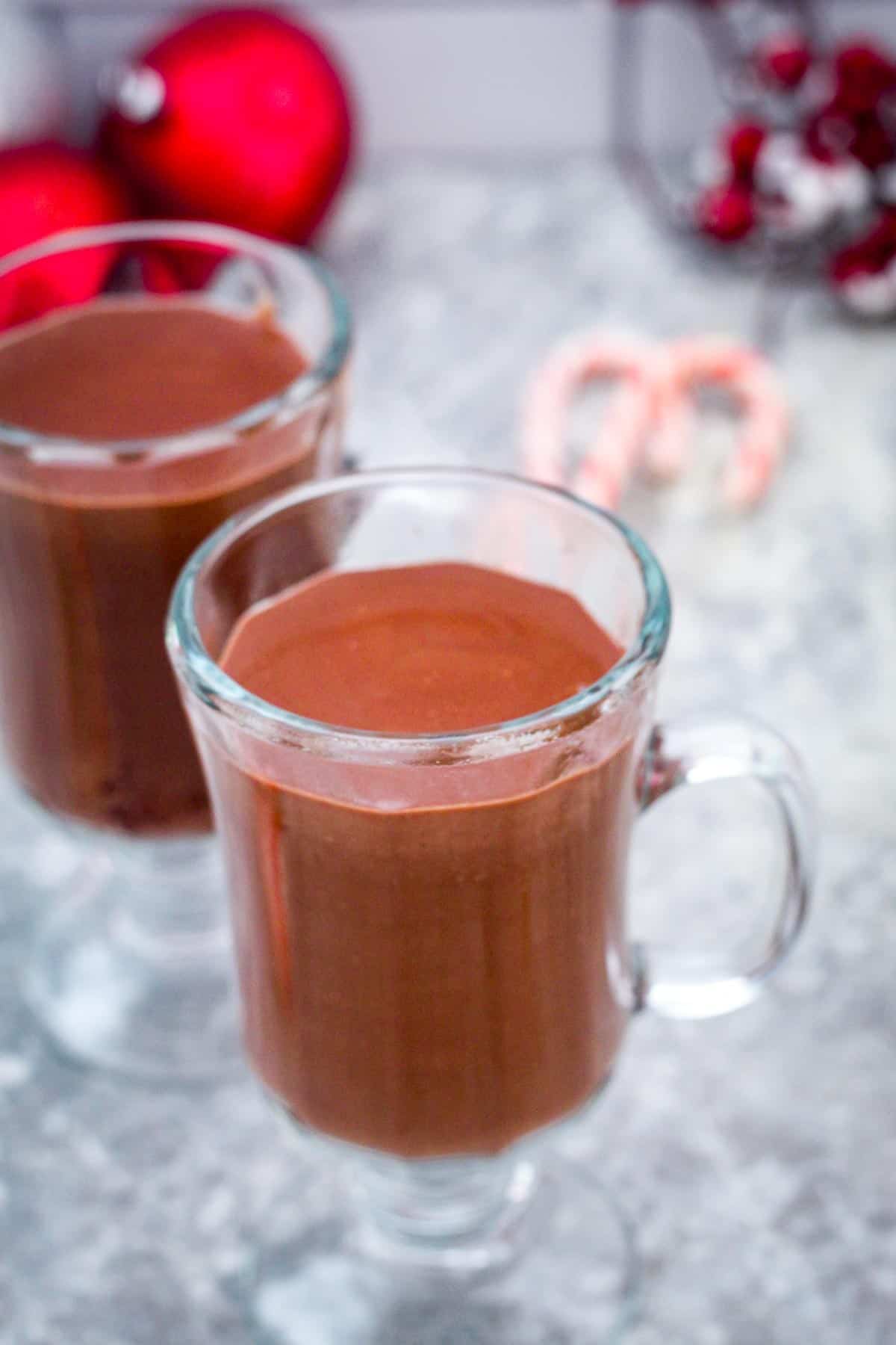 Just poured hot chocolate on a glass, looking thick and luscious. There's no toppings yet or garnishes.