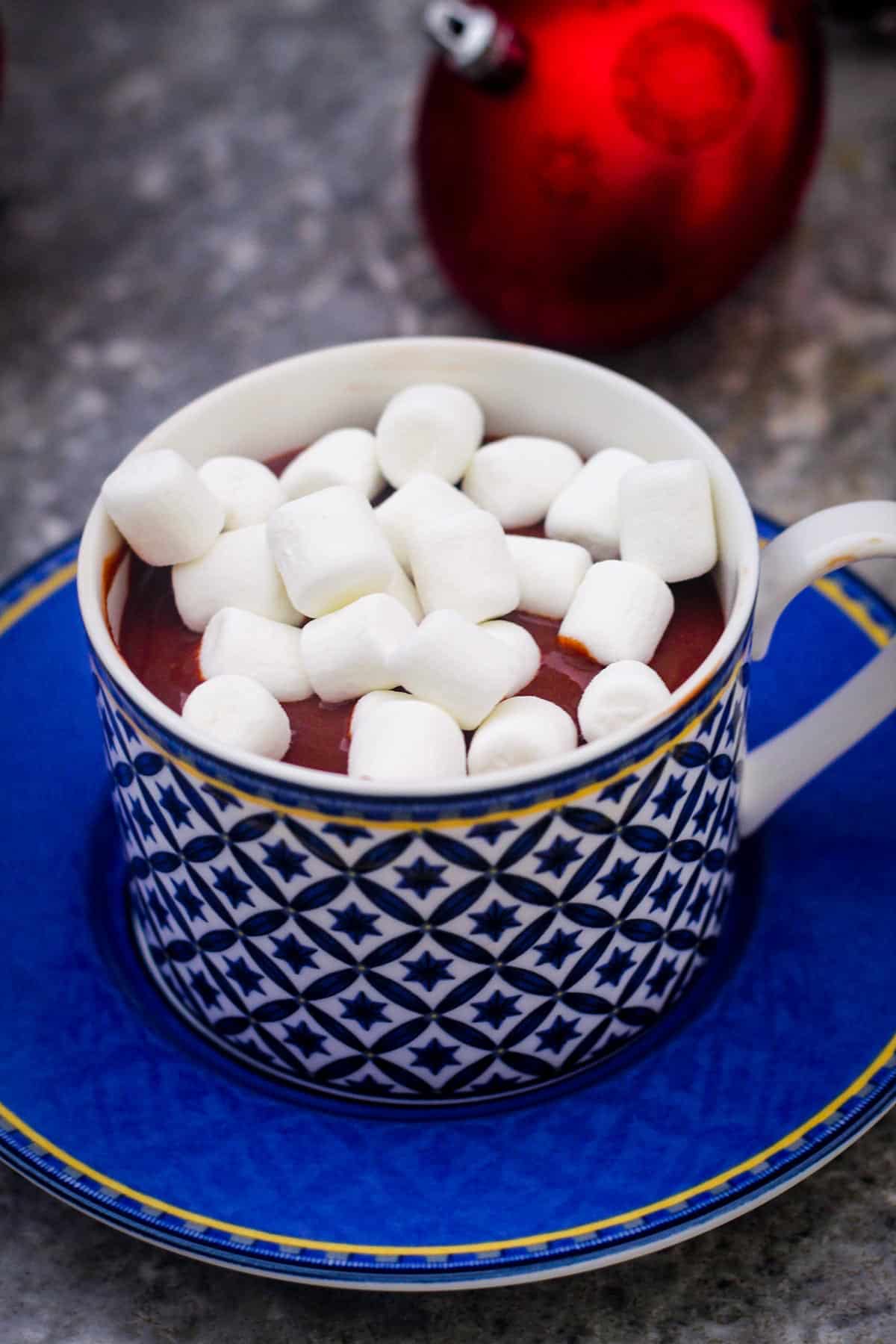 Hot chocolate with marshmallows on a cup over a saucer.