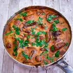 Skillet with pork tenderloins in a mushrooms sauce, garnished with fresh parsley.