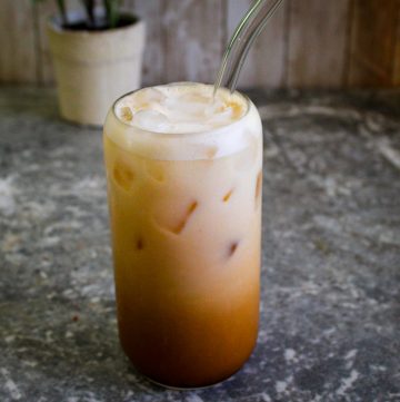 A glass with shaken espresso with hazelnut syrup over ice, served with oat milk.