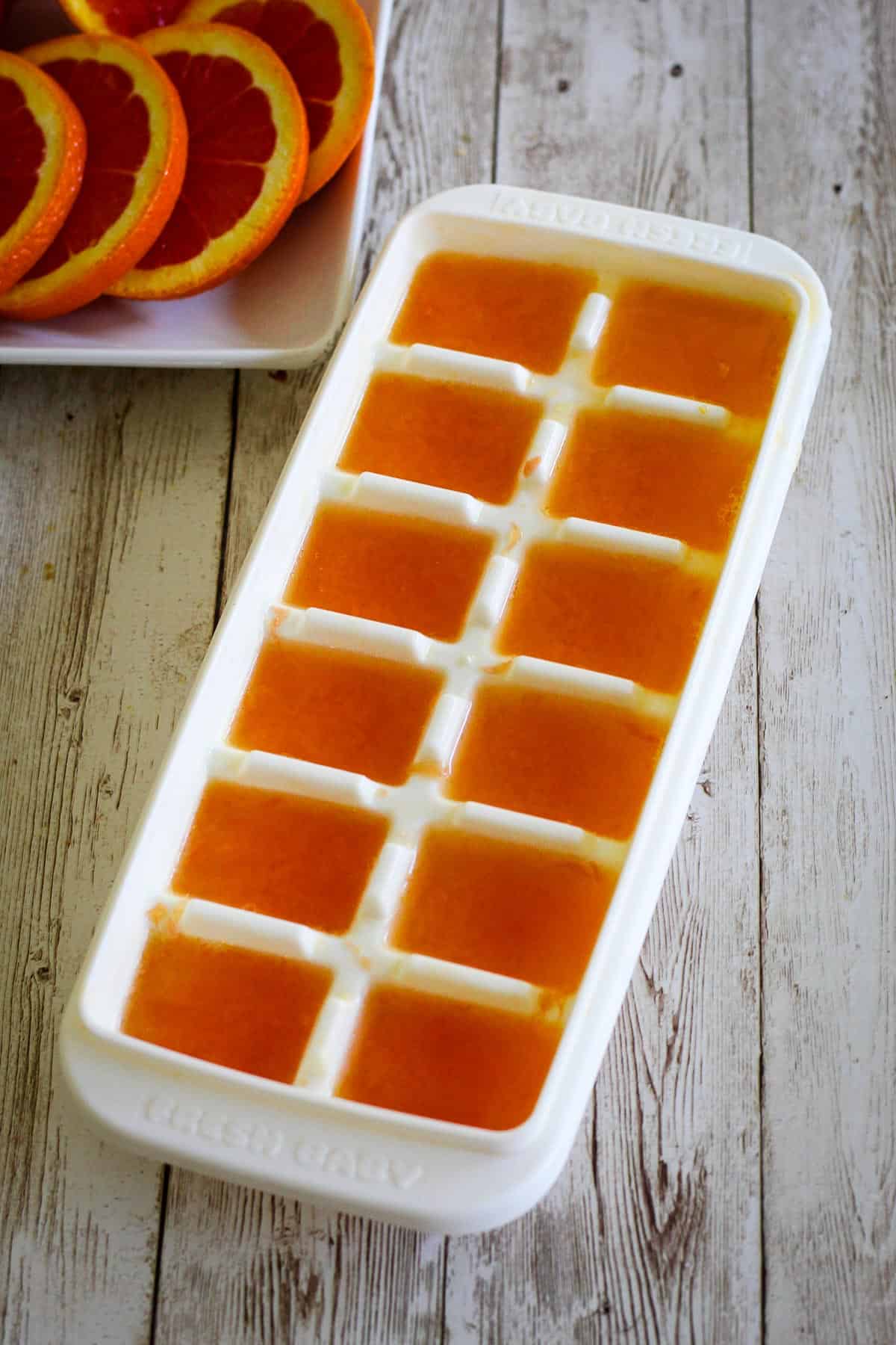 A tray of ice cubes made with orange juice. 