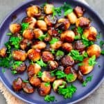 A platter of glazed and caramelized pearl onions, garnished with frehs parsley.