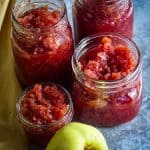 Jars of quince jams shown next to a fresh quince, on a counter.