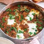 Skillet with onions casserole and eggs. garnished with parsley.