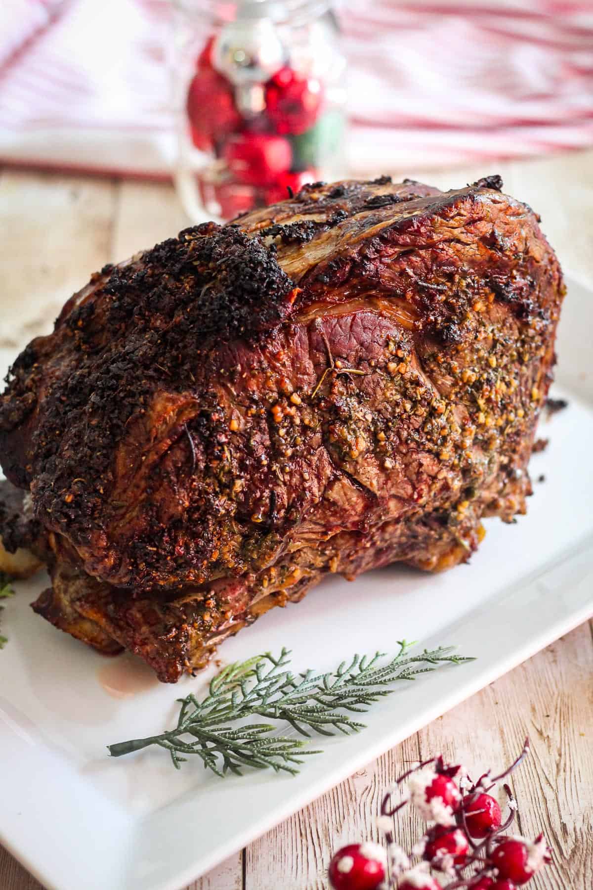 A whole standing prime rib, roasted and resting on a platter ready to carve. 