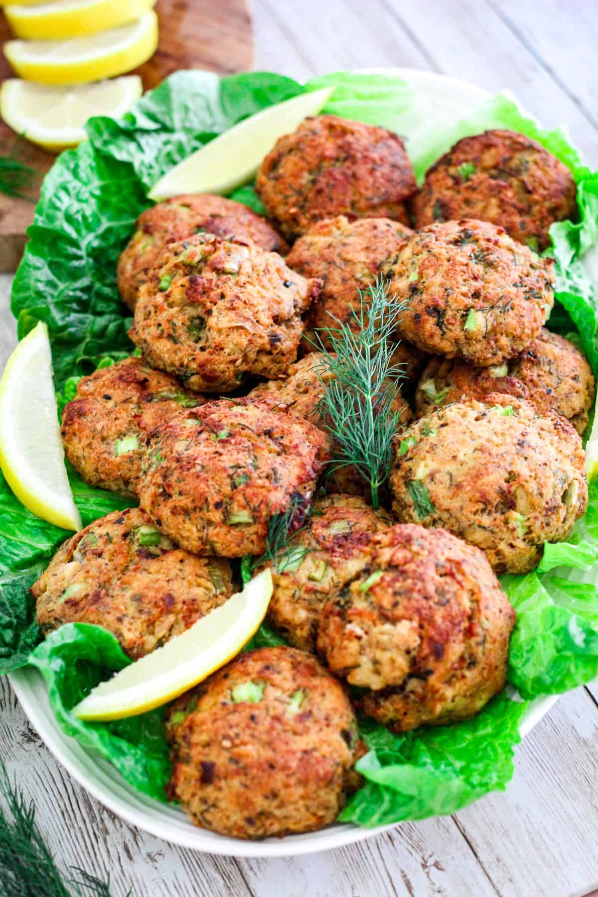 Baked salmon cakes, served on a platter over lettuce with lemon slices. 
