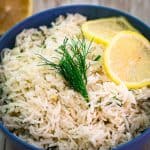 A bowl of basmati rice with dill and lemon, garnished with lemon slices.