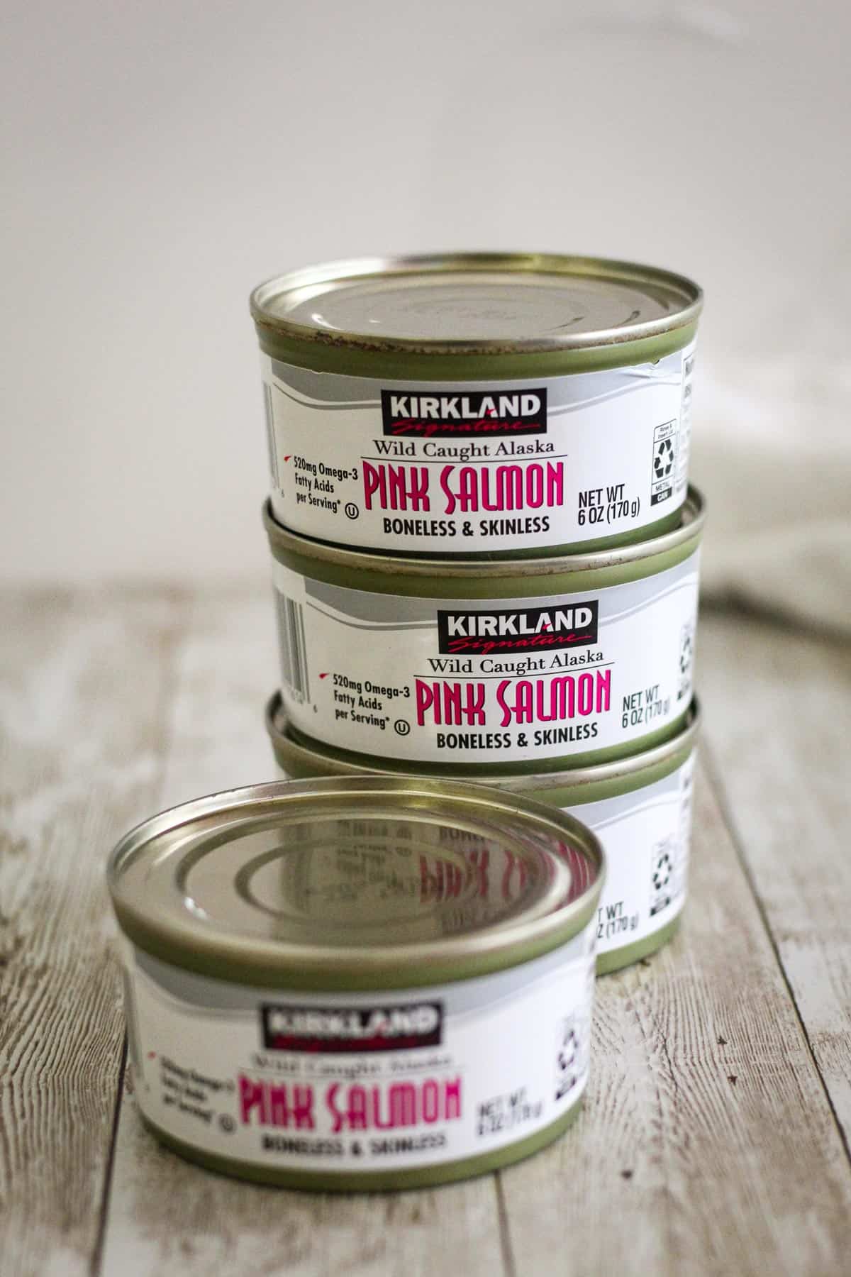 Cans of pink salmon, wild caught. The cans are Kirkland brand and are stacked on top of each other. 