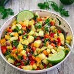 A bowl of pineapple salsa showing in detail ingredients, peppers, onions, cilantro etc etc.