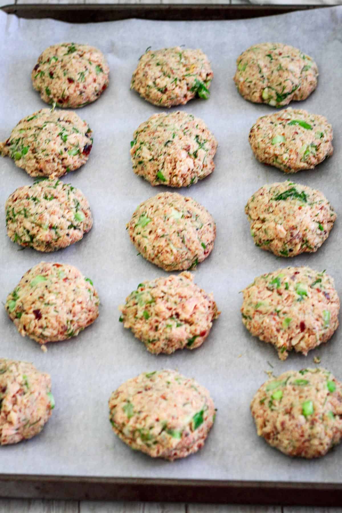 Salmon patties in a baking tray over parchment paper. 