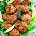 Salmon patties or salmon cakes on a platter, shown with lemon slices as garnishes over lettuce.