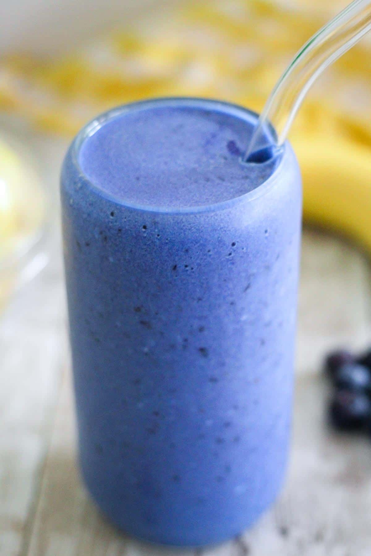 A blue smoothie in a glass jar, shown in a closeup view. 