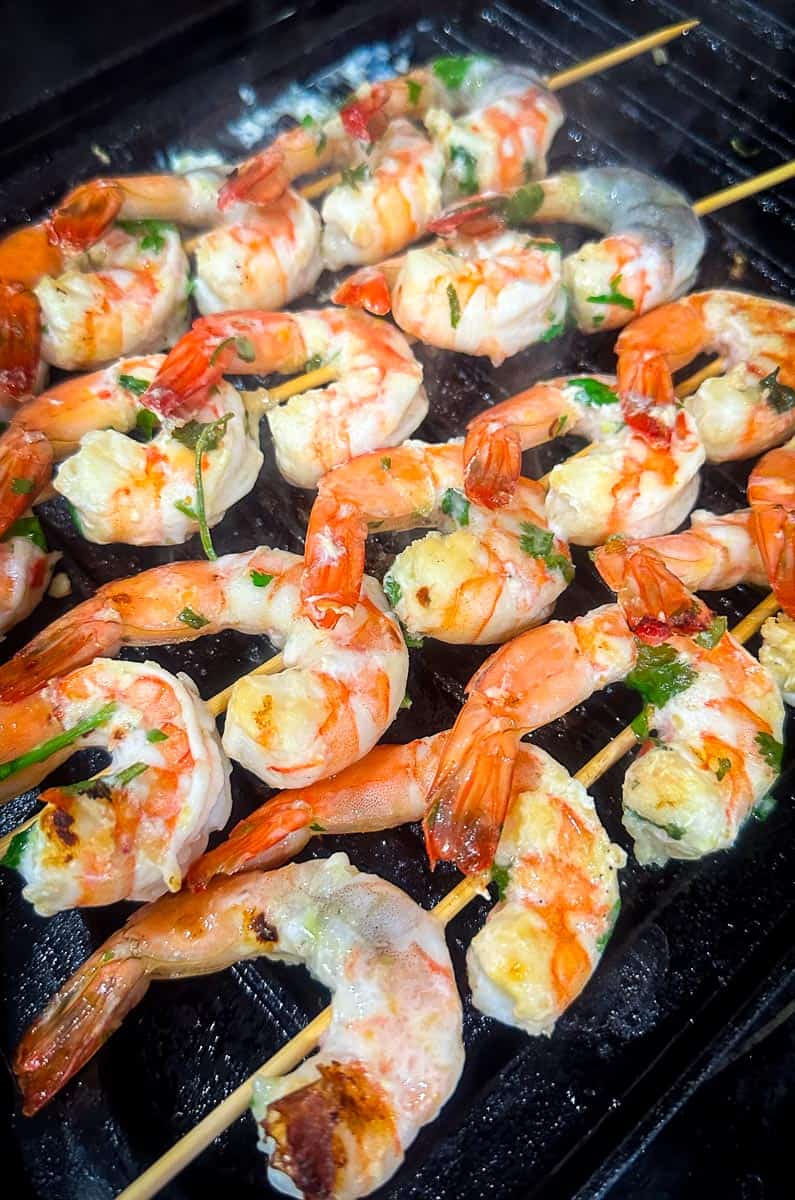 Shrimp in skewers over a cast iron griddle. 