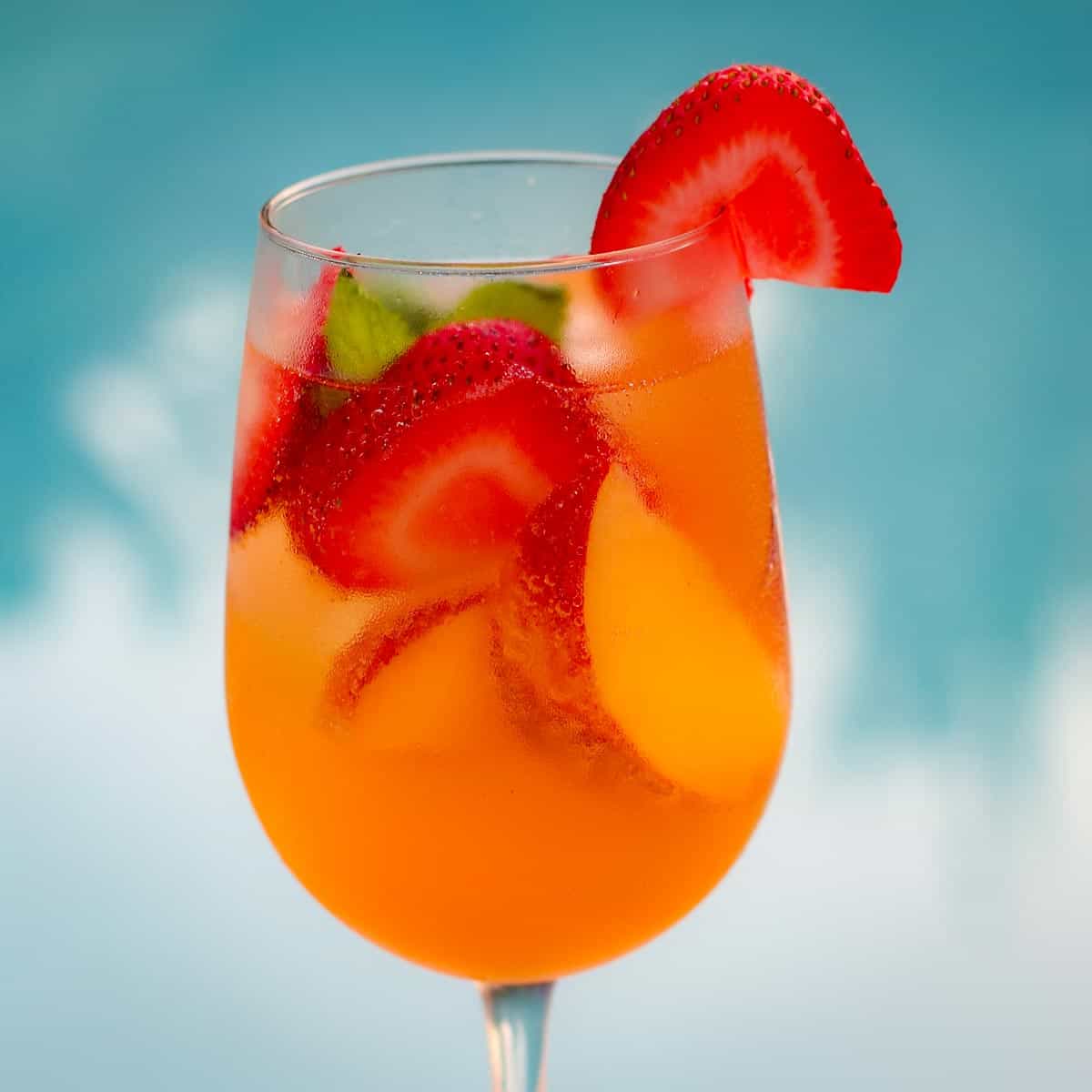 A peach rose sangria with strawberry and peach slices.