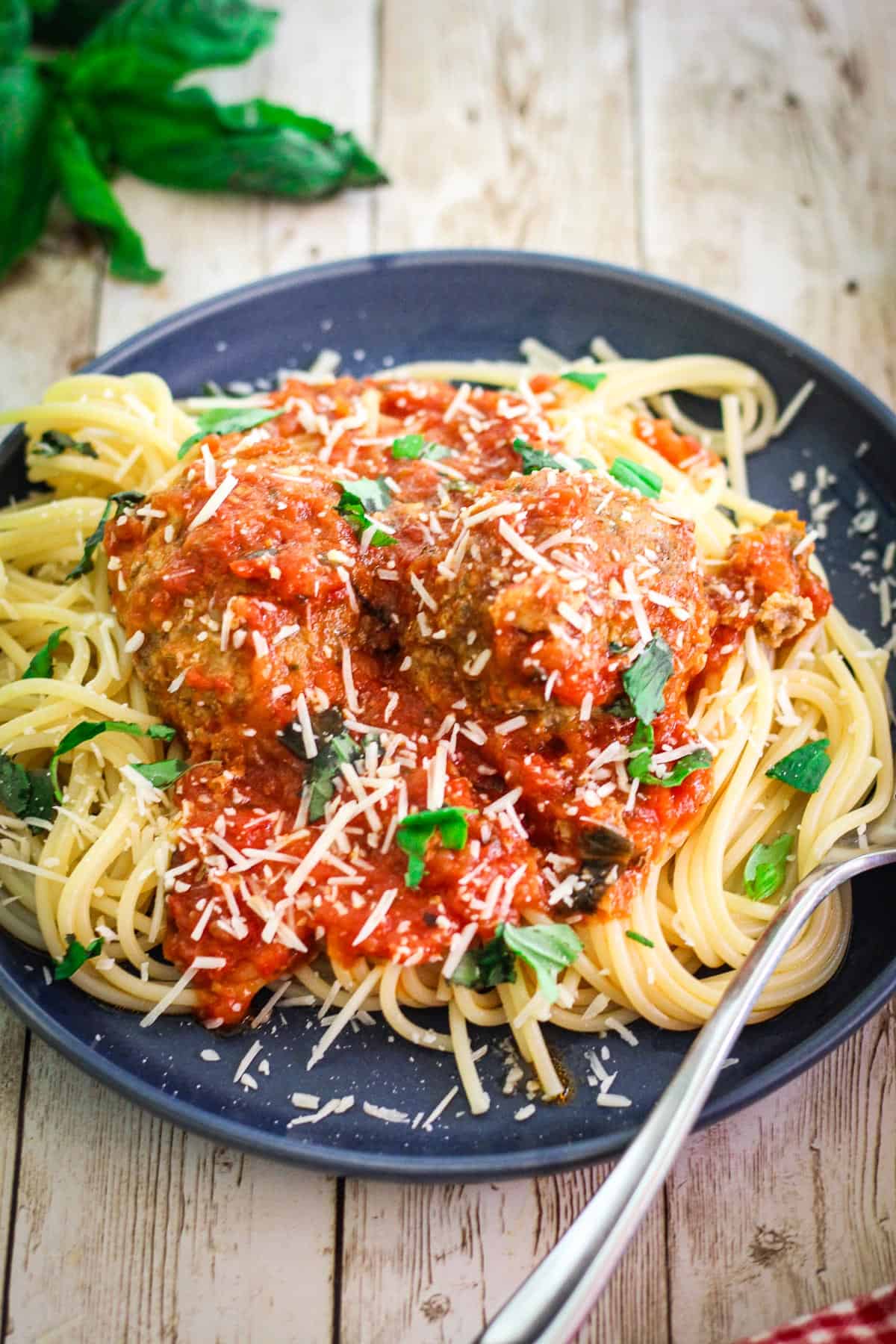 A plated spaghetti and meatballs dinner, where sauce is poured over pasta but not mixed beforehand.