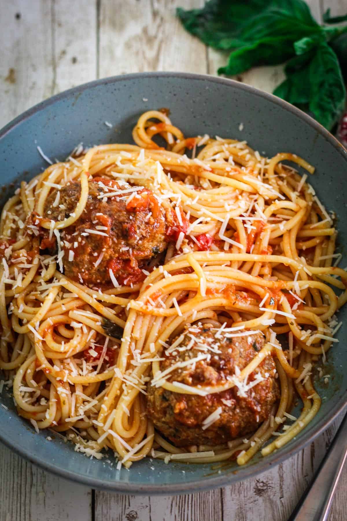 A plated spaghetti and meatballs dinner, where sauce is mixed beforehand with the pasta and served together. 