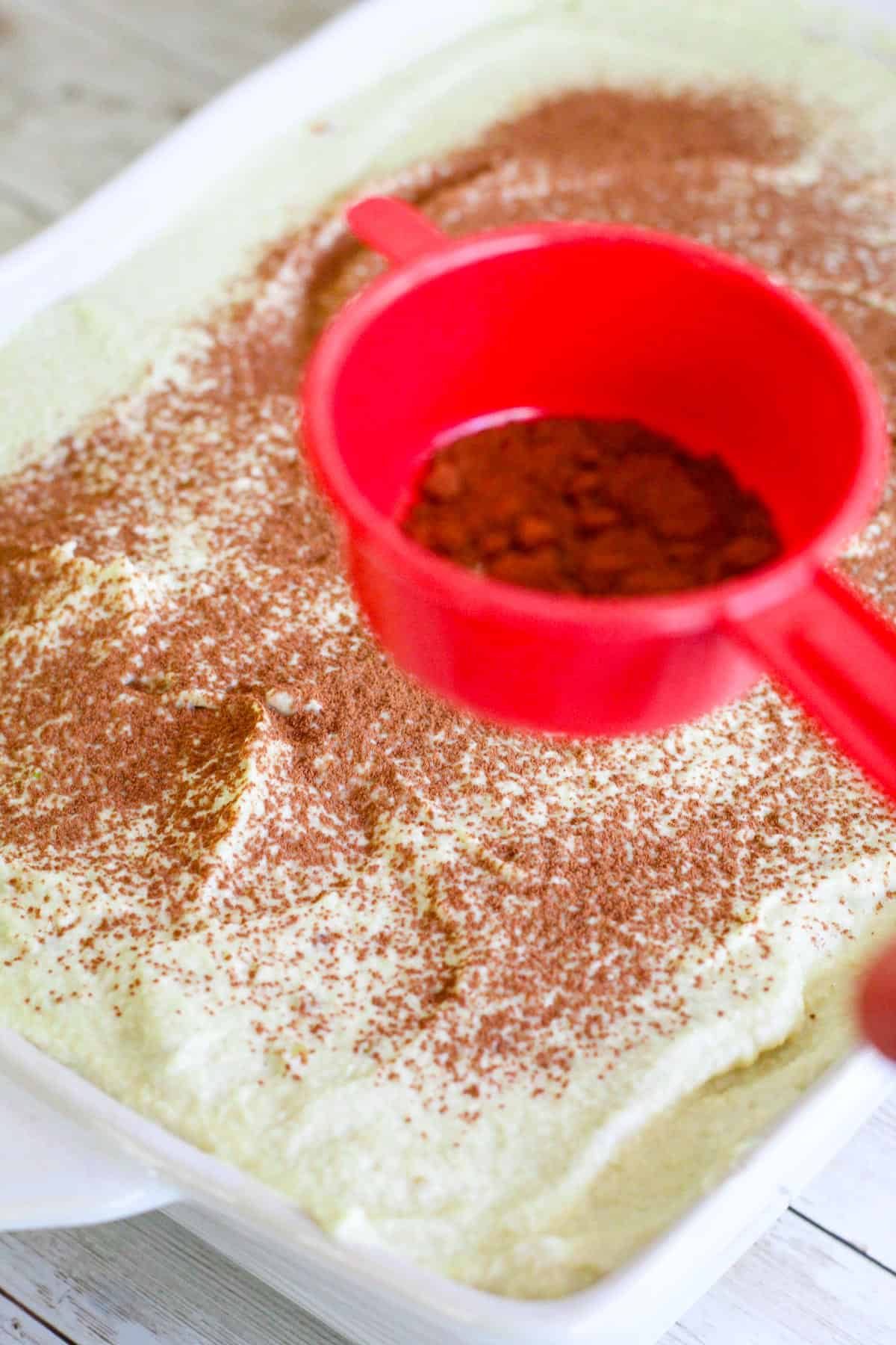 Dusting tiramisu with cocoa. 