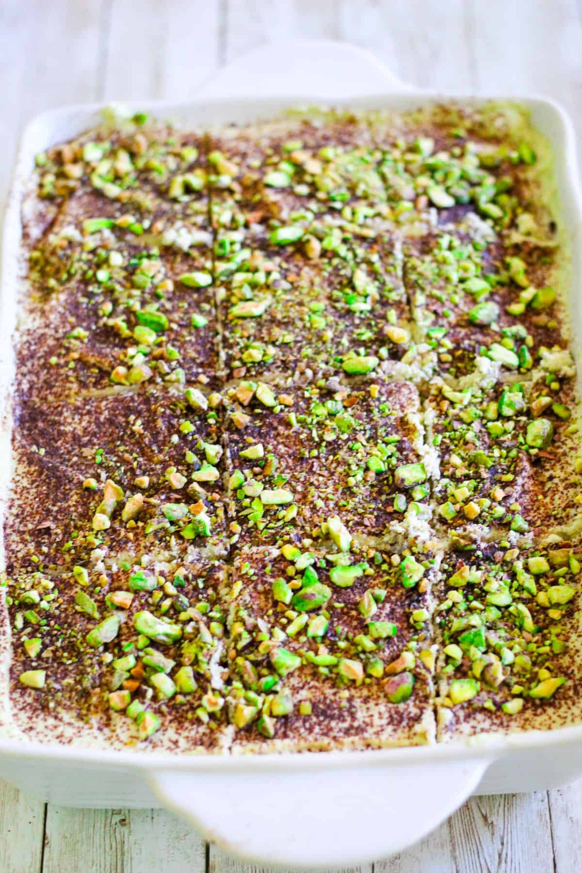 A tray of pistachio tiramisu, cut into square slices. 