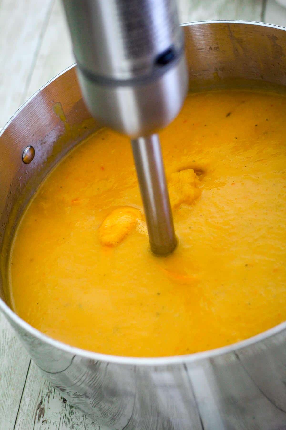 Immersion blender seen inside the soup pot turning the soup into a creamy consistency.