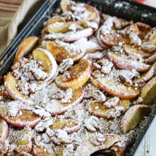 A breakfast casserole with croissants, apples and dusted with powdered sugar.