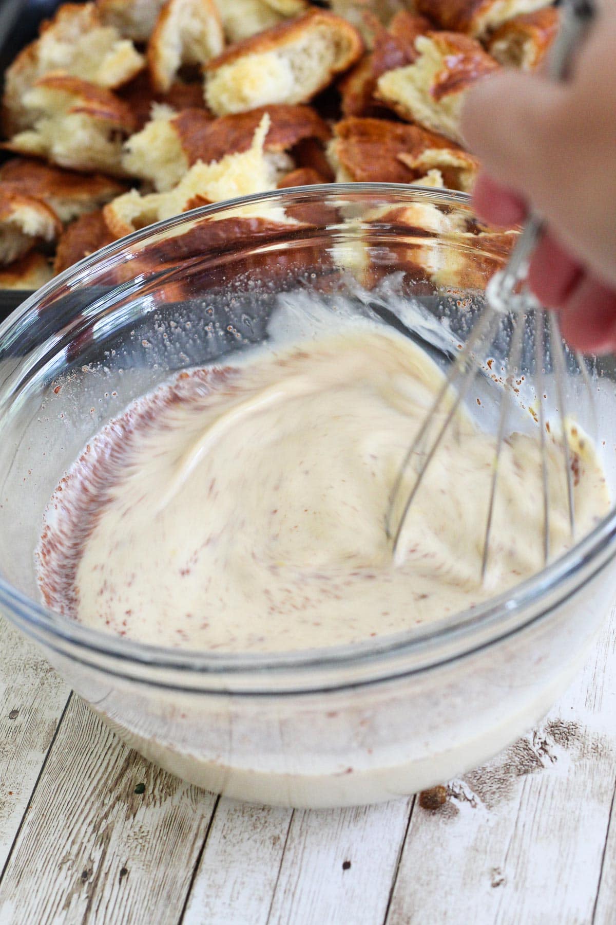Mixing ingredients for the custard, picture shows a whisk mixing all the ingredients in a glass bowl. 