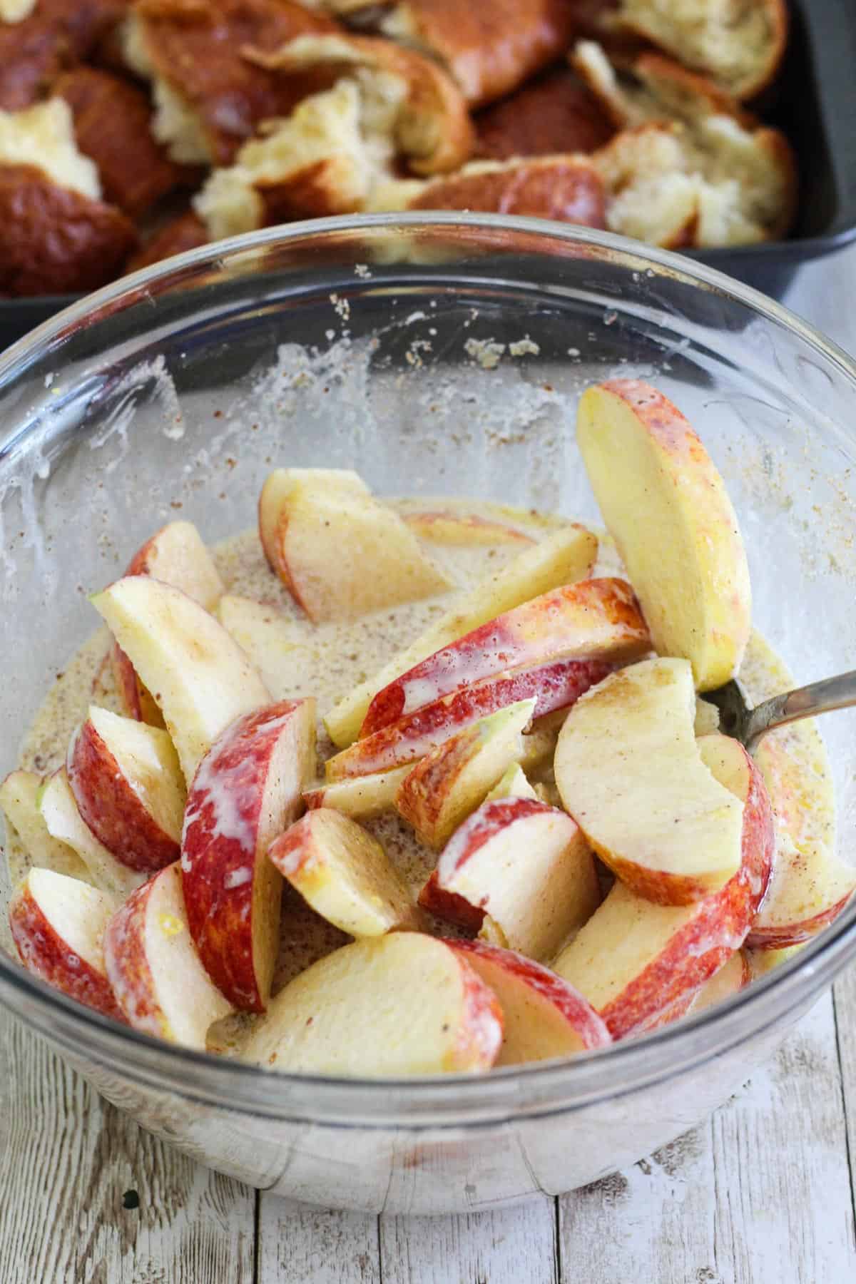 A mixing bowl showing slices apples seasoned and mixed.
