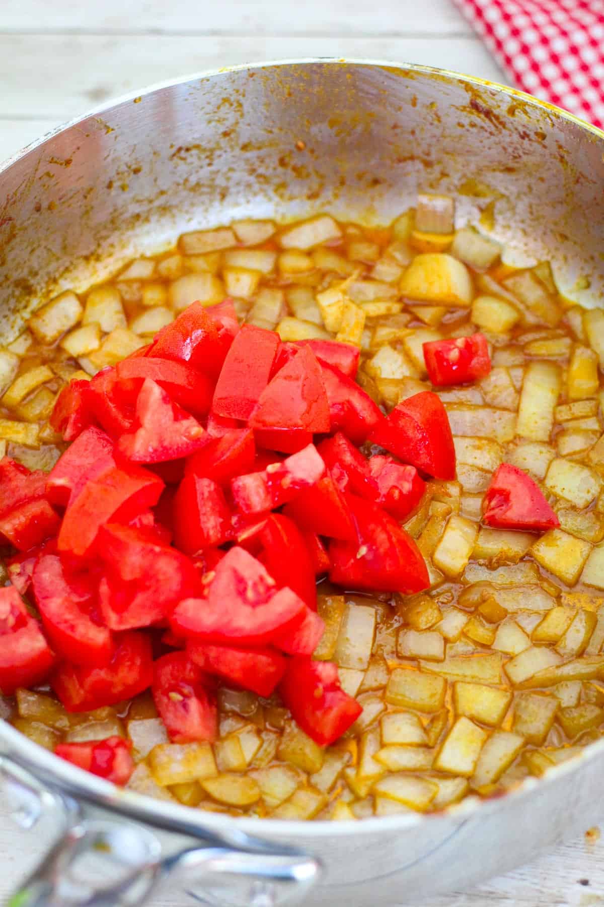 Adding tomatoes to skillet to cook with the onions. 