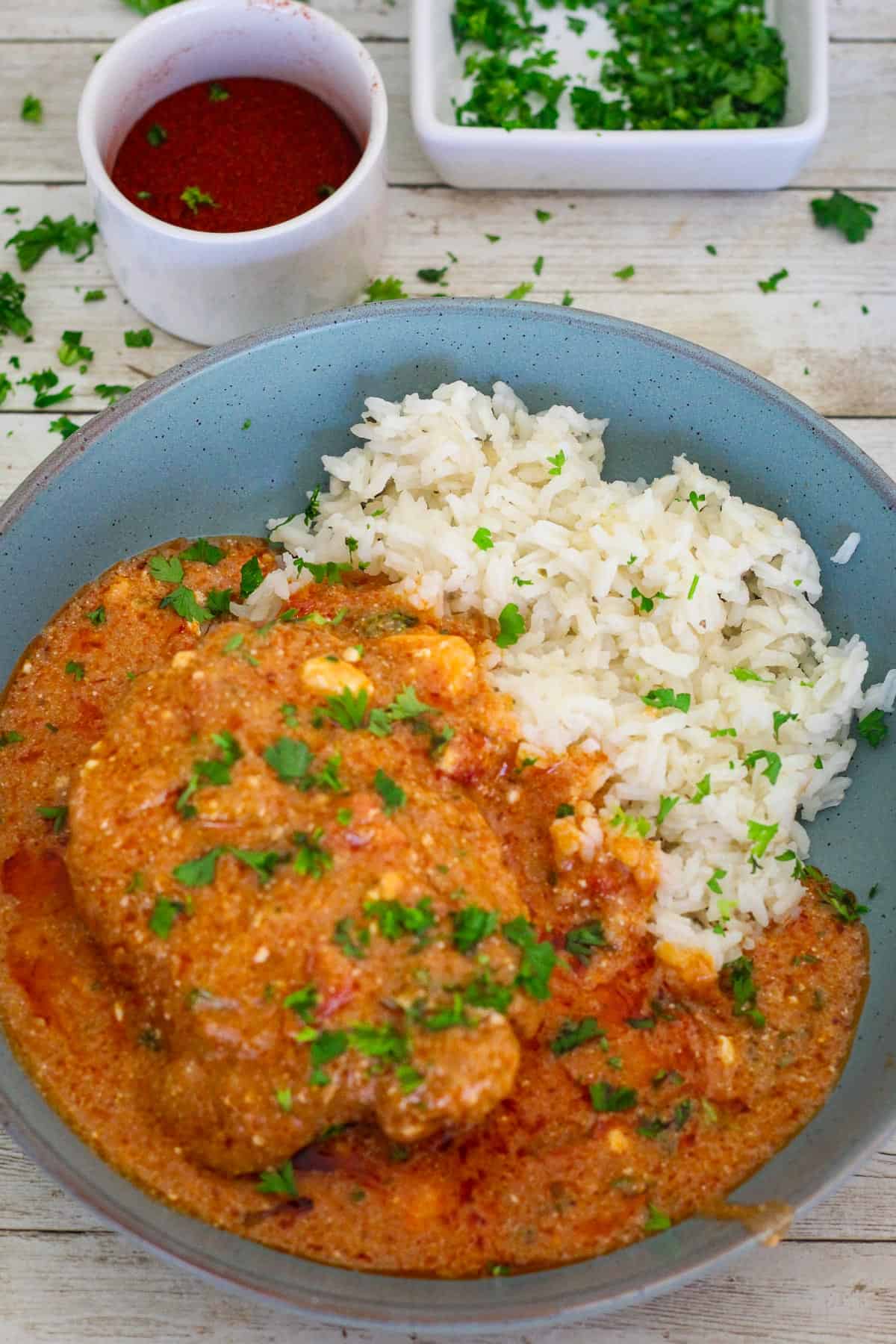 A serving of chicken paprikash with rice, garnished with fresh parsley! 