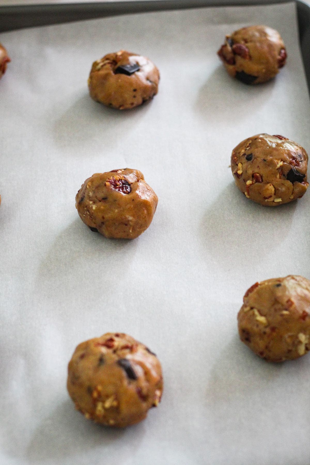 Baking sheet with parchment paper, showing spaced out cookie dough balls ready to bake.
