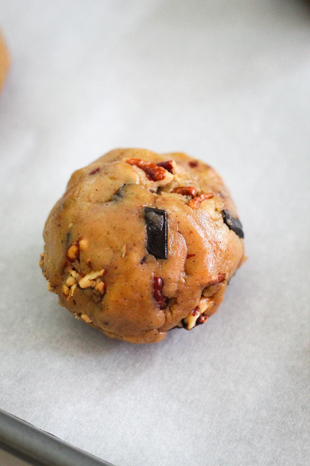 Cookie dough made into a ball, placed on a parchment paper.