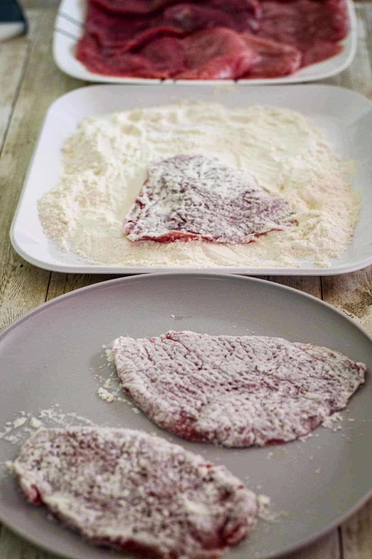 A three plate process that shows raw veal, then veal dredged in flour, then veal cutlet in the final plate ready to go on the skillet.