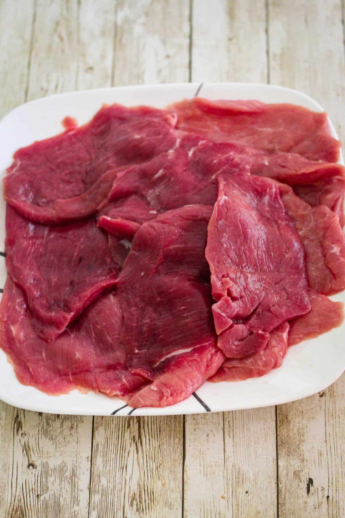 Raw veal cutlets on a plate.