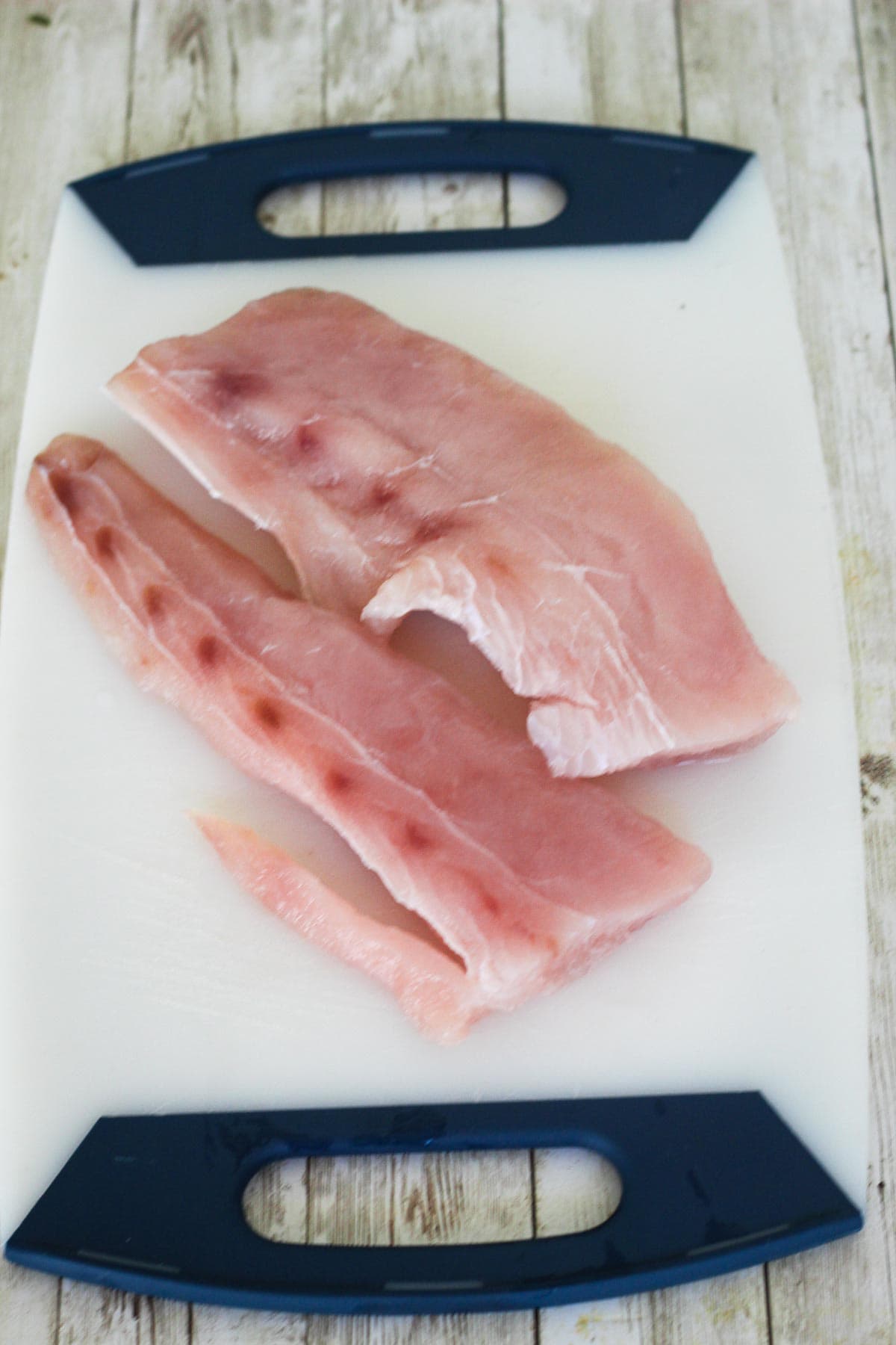 Two large mahi mahi fillets on a cutting board.