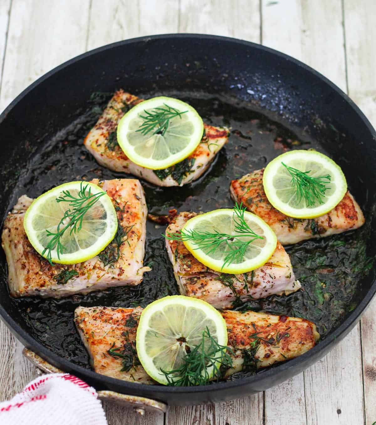 Once sauce is finalized, the seared mahi mahi fillets are added back in the pan. This picture shows the moment the fillets are back over the sauce and garnished with lemon and dill.