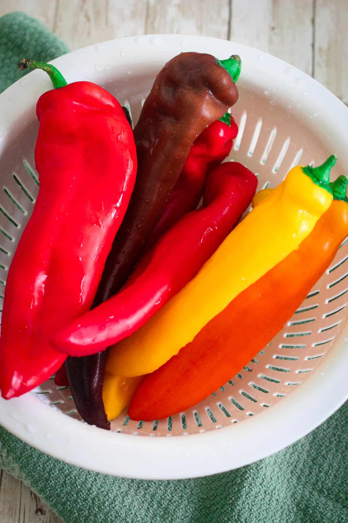 Long peppers, different colors in a colander.