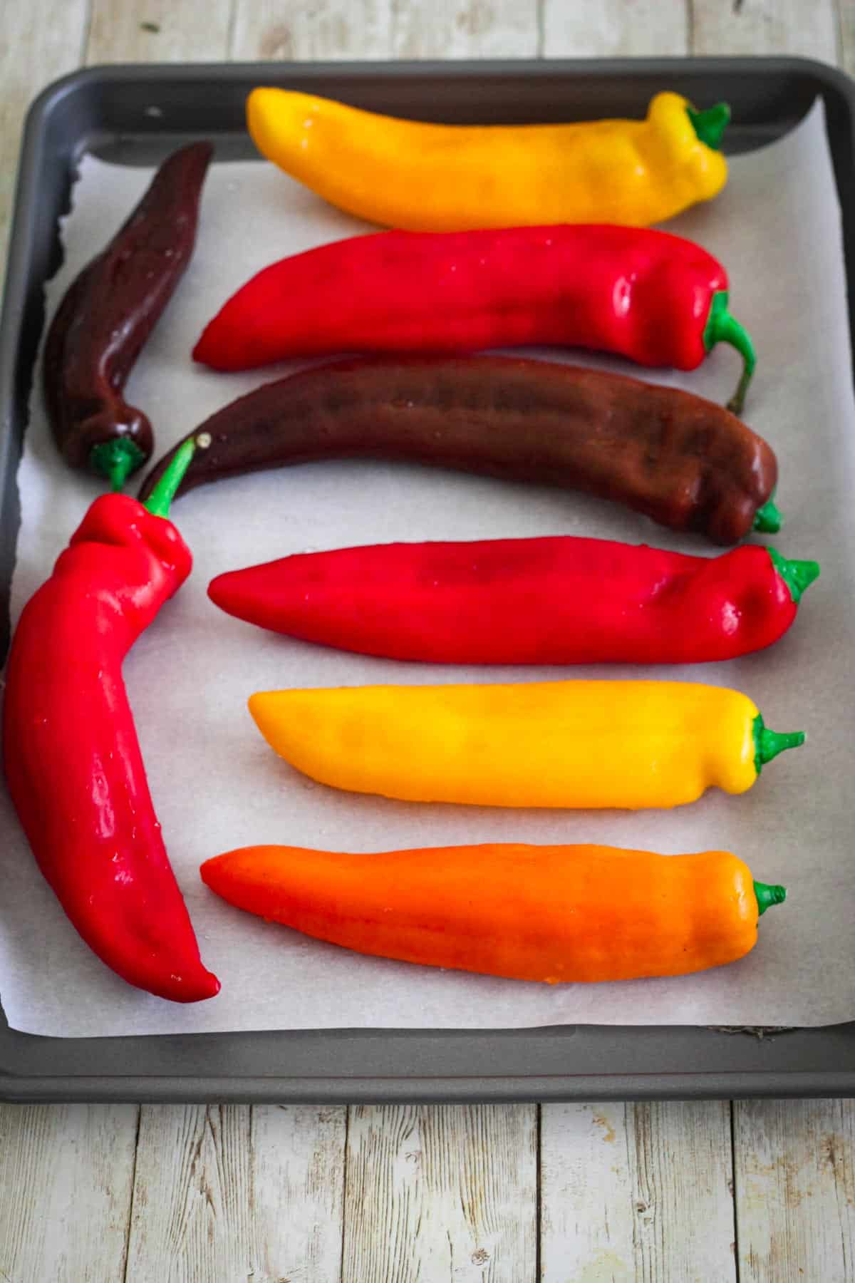 Peppers lined up over parchment paper in a baking tray.